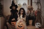 Enfants déguisés en sorcière, fantôme, squelette, et zombie assis sur des marches, prêts pour Halloween.