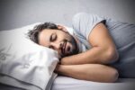 Homme dormant paisiblement sur un oreiller blanc, représentant le sommeil réparateur.