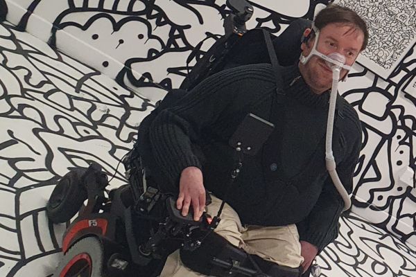 Guillaume en fauteuil roulant électrique, sous assistance respiratoire, symbole de force et d’autonomie malgré la myopathie de Duchenne