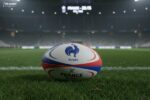 Ballon de rugby officiel de l'équipe de France posé sur la pelouse d'un stade de nuit sous les projecteurs